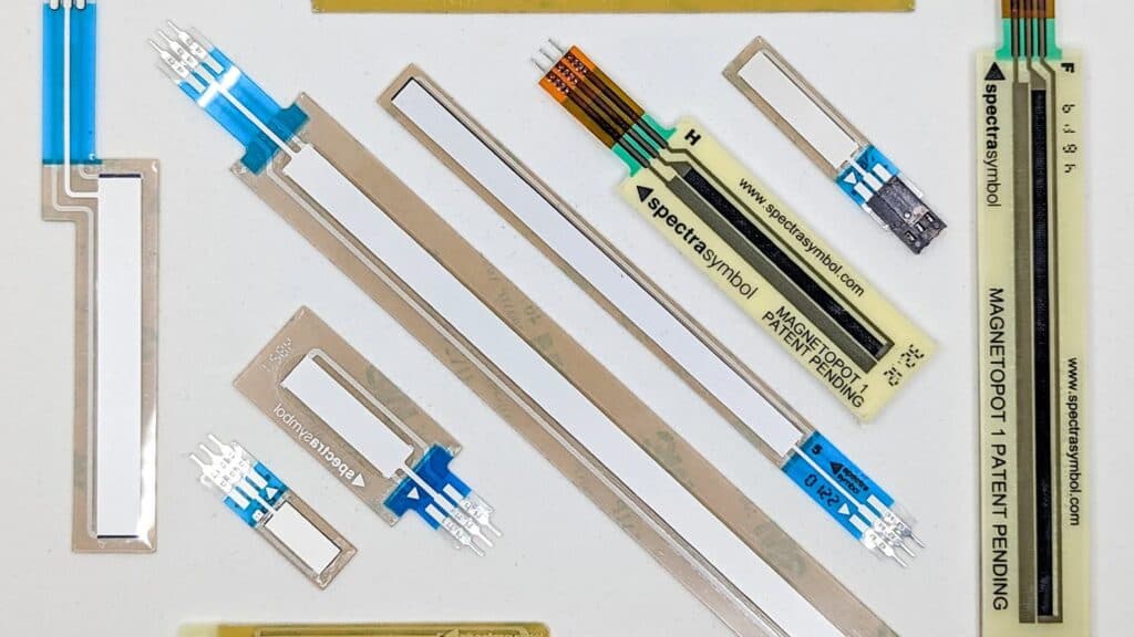Various Spectra Symbol potentiometers including SoftPot membrane linear sensors, MagnetoPot magnetic position sensors, and flexible bend sensors displayed on a white background.